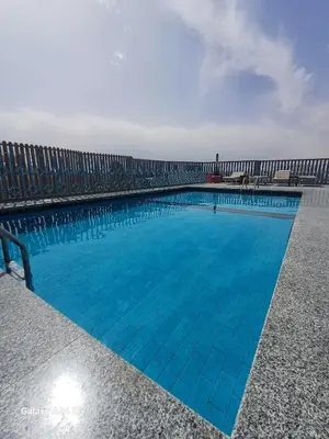 a swimming pool with blue water and chairs at Palm Inn Hotel Hurghada in Hurghada