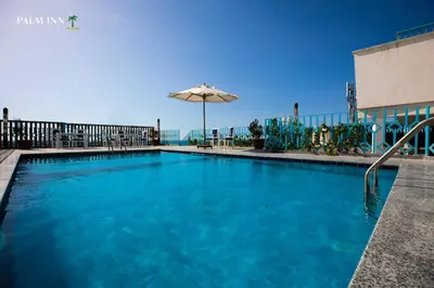 a large swimming pool with an umbrella and chairs at Palm Inn Hotel Hurghada in Hurghada