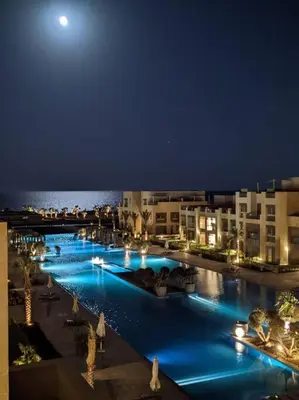 a large swimming pool with blue lights at night at Mangroovy - Spacious Boho 2 BR Pool view in Hurghada