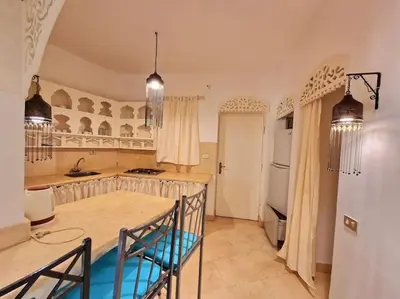 a kitchen with a table and a white refrigerator at Cozy apartment in Downtown Gouna in Hurghada