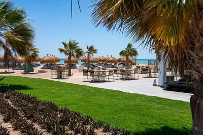 a patio with tables and umbrellas on the beach at Cozy 1 Bedroom Ground Floor Apartment with Pool in Hurghada