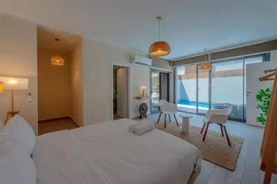 a bedroom with a large white bed and chairs at Tropical 2BR Paradise in Bali, El Gouna. Pool, Patio & BBQ in Hurghada