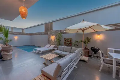 a patio with a couch and an umbrella and a pool at Tropical 2BR Paradise in Bali, El Gouna. Pool, Patio & BBQ in Hurghada