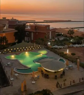 a large swimming pool with umbrellas in front of a building at Turtle beach apartment in Hurghada