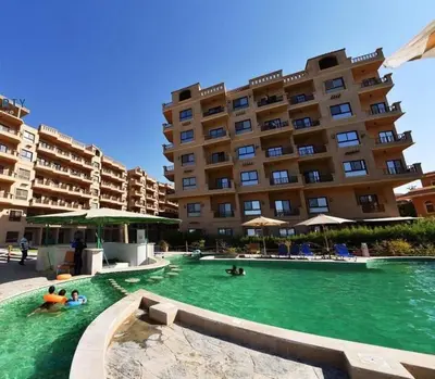 a swimming pool in front of a large building at Turtle beach apartment in Hurghada