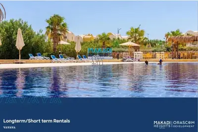 a pool with chairs and umbrellas in a resort at 2 bedroom modern flat at Makadi heights in Hurghada