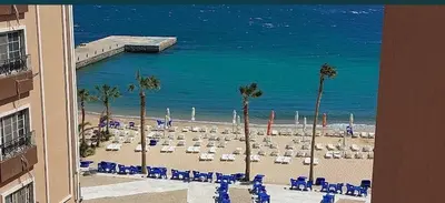 a beach with chairs and palm trees and the ocean at Juliana resort beach - Julia apartment in Hurghada