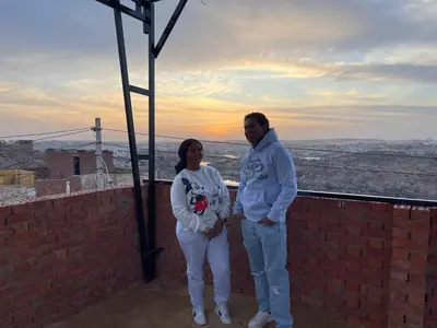 a man and a woman standing on a brick wall at king kassem nubian guest house in Aswan
