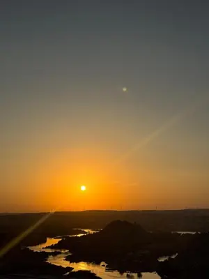 a sunset in the desert with the sun setting at king kassem nubian guest house in Aswan