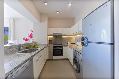 a kitchen with white cabinets and a refrigerator at Cheerful space with a huge garden and pool in Hurghada
