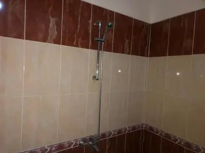 a shower in a bathroom with brown tiles at Obelisk house in Jazīrat al ‘Awwāmīyah