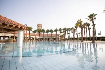 a large swimming pool with palm trees and a building at Ladybird - Veranda Skyline in Hurghada