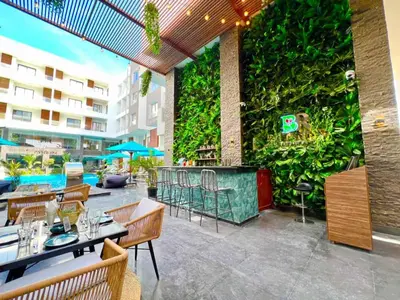 an outdoor patio with tables and chairs and a green wall at Imperial Resort Apartment XL 1 Bed in Hurghada