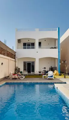 a house with a swimming pool in front of a house at Al Baba Nile Villa in Luxor
