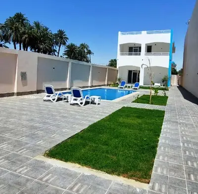 a house with a swimming pool and some chairs at Al Baba Nile Villa in Luxor