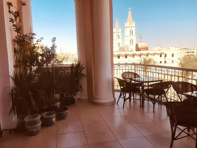 a balcony with tables and chairs and a view of a building at Alam B&B Luxor in Luxor