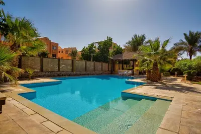 a swimming pool in a yard with palm trees at Modernes Apartment in El Gouna - South Marina in El Gouna