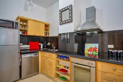 a kitchen with stainless steel appliances and wooden cabinets at Modernes Apartment in El Gouna - South Marina in El Gouna