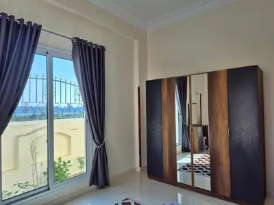 a room with a mirror and a large window at Nille and Garden View Apartment in Jazīrat al ‘Awwāmīyah