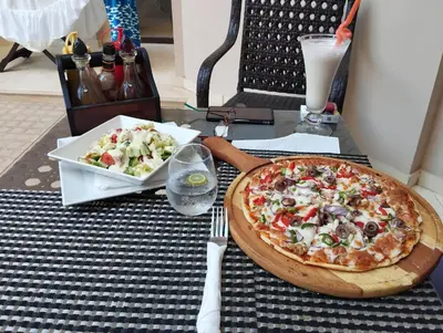 a pizza on a table with a plate of salad at Studiowohnung auf Poolebene in Hurghada