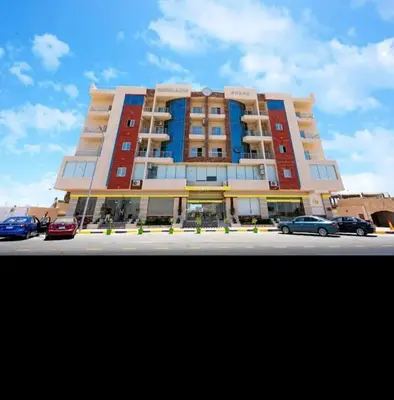 a large building with cars parked in a parking lot at Kazpilkna Beach Neighborhoods in Hurghada