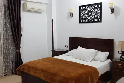 a bedroom with a bed with a brown blanket on it at Elminaa Residents 2 in Luxor