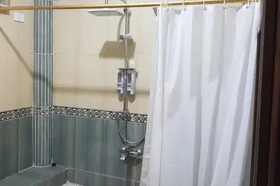 a shower with a white shower curtain in a bathroom at Elminaa Residents 2 in Luxor
