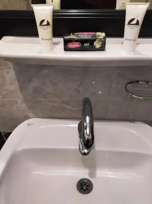a bathroom sink with a fosset and two cups at El Minaa Residents 5 in Luxor