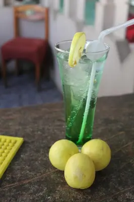 a glass of green liquid with a banana on a table at Emilio Hotel in Luxor