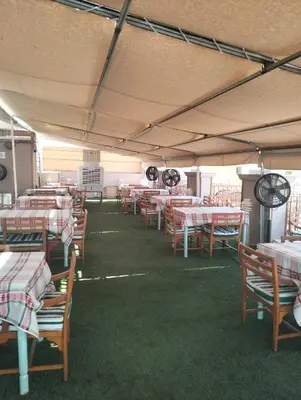 a dining room with tables and chairs and green grass at Emilio Hotel in Luxor