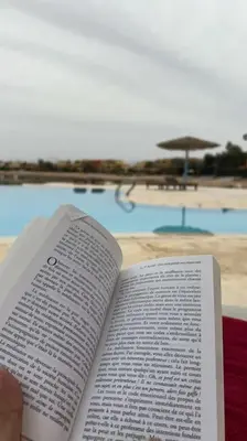 a person holding a book in front of a pool at Vue magnifique, confort unique in Hurghada