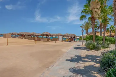 a beach with palm trees and umbrellas on the beach at Beach Front Paradise - 3 master beds - Abu Tig Marina - El Gouna in Hurghada