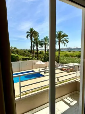 a view of a pool and palm trees from a window at Royal Nile Suites - Luxury Nile View 2 in Luxor