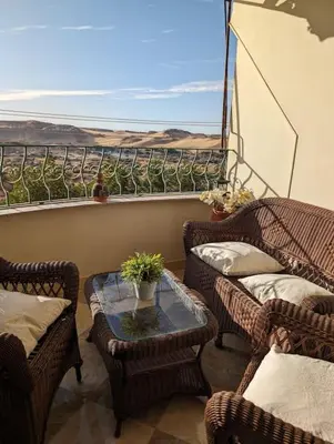 a balcony with wicker chairs and a table with a view at Aswan Nile view Family apartment in Aswan