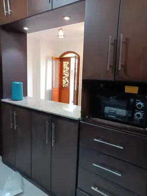 a kitchen with wooden cabinets and a microwave at HW.Appartment in Hurghada
