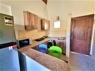 a small kitchen with wooden cabinets and green stools at 2 bedroom quiet flat at makadi heights in Hurghada