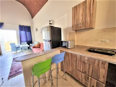 a kitchen with a counter and two green chairs at 2 bedroom quiet flat at makadi heights in Hurghada