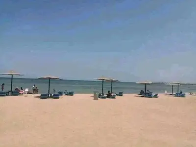 a beach with many chairs and umbrellas and the ocean at Apartment in Cecelia Resort in Hurghada