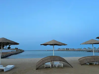 two chairs and umbrellas on a beach with the ocean at Luxury Seaview Apartment with Pool Scandic Resort Hurghada in Hurghada