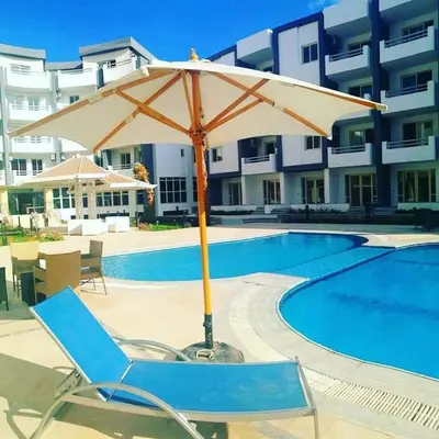 a chair and an umbrella next to a swimming pool at Studio In sky el Gandoul compound in Hurghada