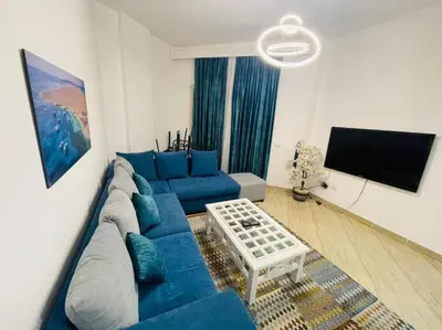 a living room with a blue couch and a flat screen tv at Velký apartmán 50 m od pláže s přístupem zdarma- Sahl Hasheesh Hurghada resort Andalusie in Hurghada