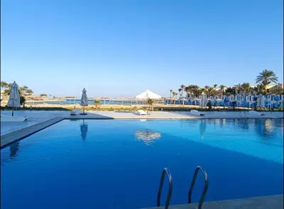 a large swimming pool with blue water and chairs at Scandic Resort in Hurghada