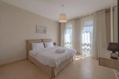 a bedroom with a bed and a large window at Modern 1BR, Mangroovy, Gouna - 1BR, Pool, & Beach in Hurghada