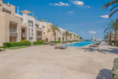a resort with a swimming pool and palm trees at Ground Floor 2BR Apt in Mangroovy, Pool & Beach in Hurghada