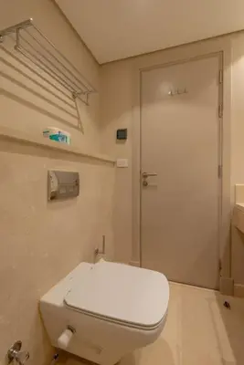 a bathroom with a white toilet and a door at Ground Floor 2BR Apt in Mangroovy, Pool & Beach in Hurghada