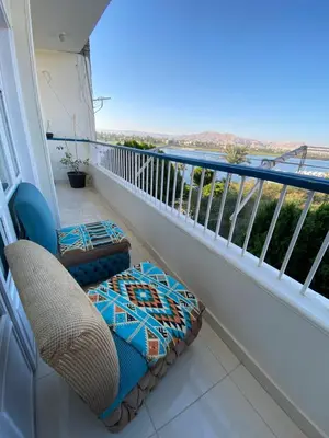 a balcony with a chair and a couch and a view at luxor Nile view duplex apartment in Luxor
