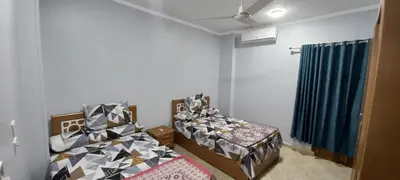 a room with two beds and a window with blue curtains at Ikea flat 9 in Hurghada