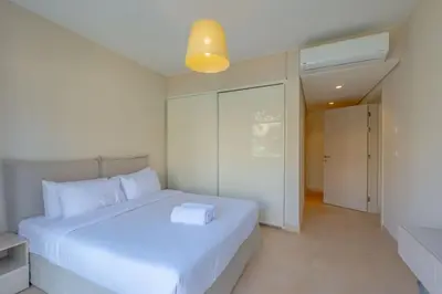 a white bedroom with a white bed and a light at Pool Front 2BR in Mangroovy - El Gouna, Beach Access in Hurghada