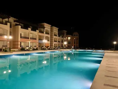 a large swimming pool in front of a building at night at S 22 Marina City in Port Ghalib
