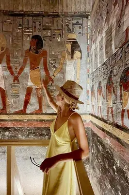 a woman in a yellow dress standing in front of a painting at live Nile in style Nile cruise in Luxor and Aswan in Luxor